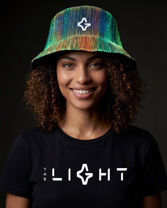 Person wearing a multicolor illuminated fiber-optic bucket hat and a black T-shirt with “THE LIGHT” logo against a dark back