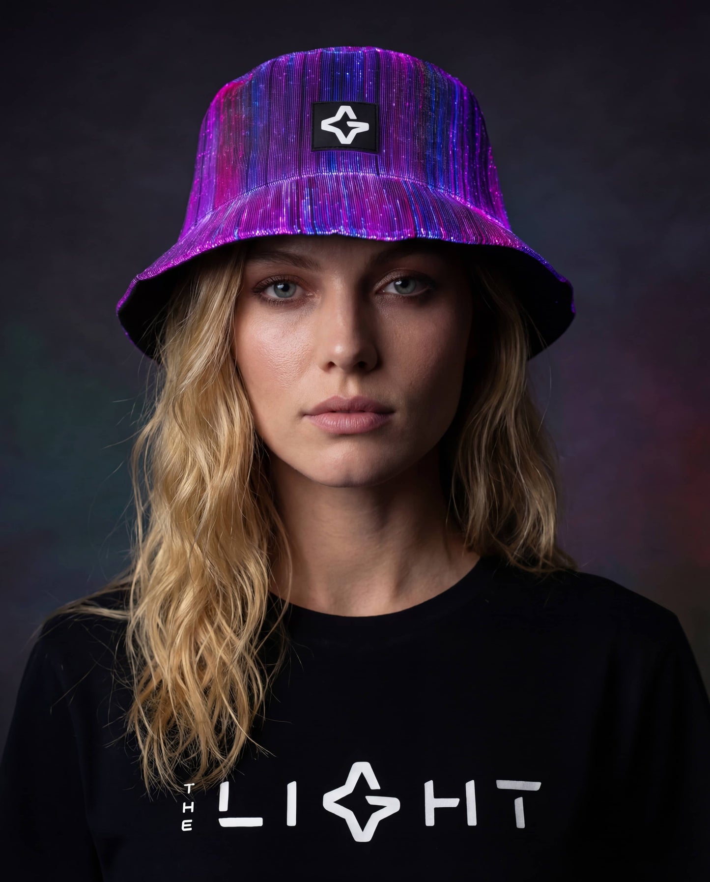 Person wearing a purple fiber optic light-up bucket hat with THE LIGHT logo, shown against a dark background