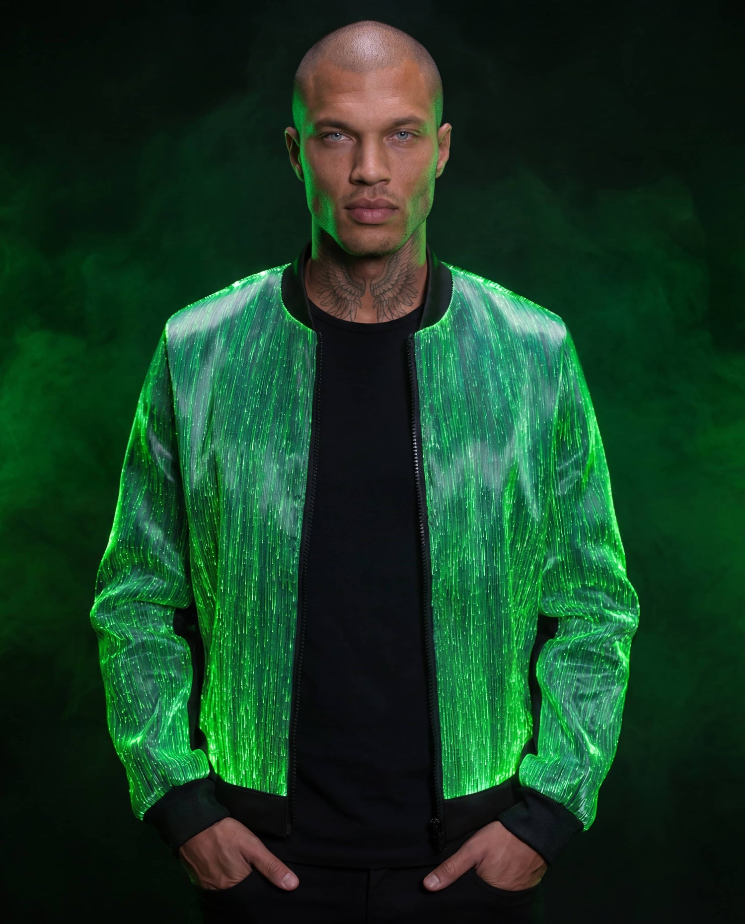 Model wearing a glowing green fiber-optic bomber jacket, standing against a dark smoke-filled background