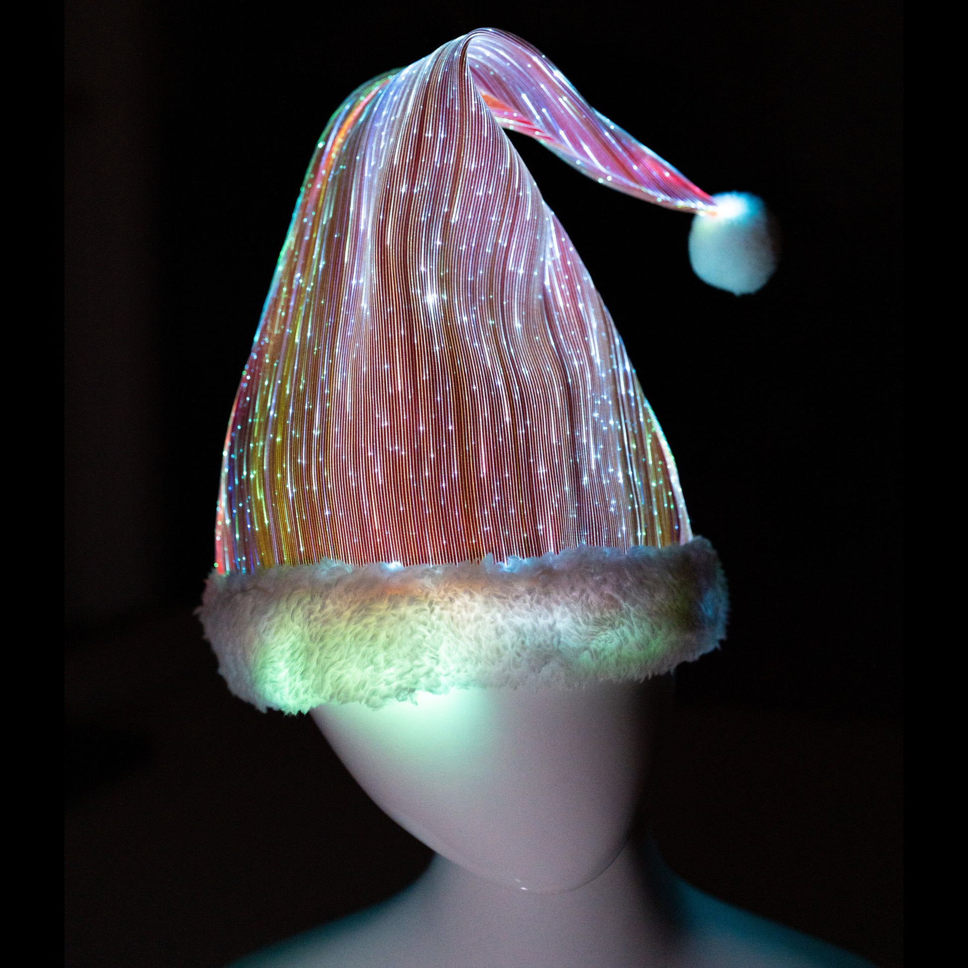 Fiber optic light-up Christmas Santa hat illuminated in multicolor light on a mannequin head against a dark background