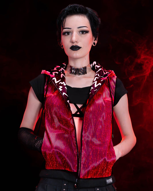 Woman wearing a black fiber optic light up sleeveless hoodie glowing in red light against a dark background