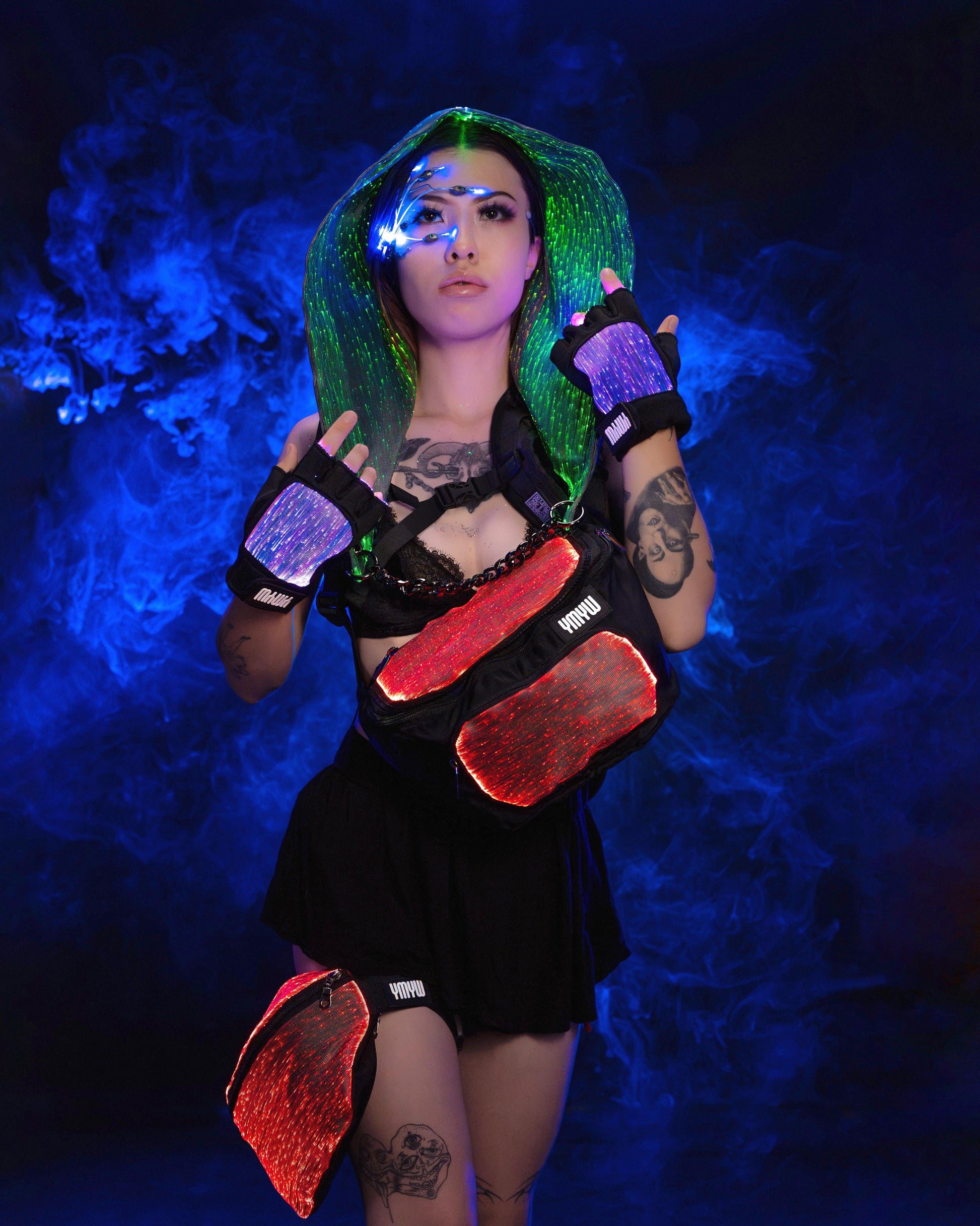 Woman wearing fiber optic light up fanny pack illuminated in red and other items in various colors and purple light against a dark background