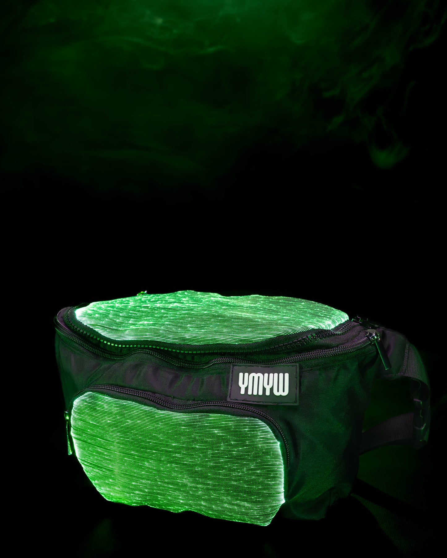 Fiber optic light up waist bag illuminated in green light with "YMYW" branding on a dark background