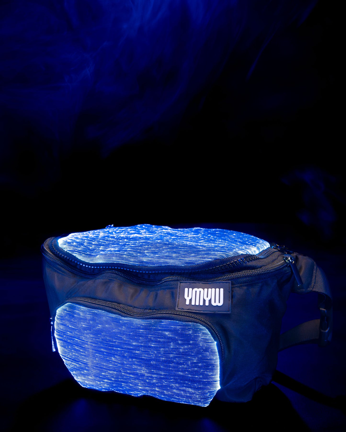 Fiber optic light up waist bag illuminated in blue light with "YMYW" branding on a dark background