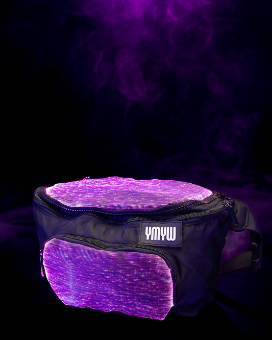 Fiber optic light up waist bag illuminated in purple light with "YMYW" branding on a dark background