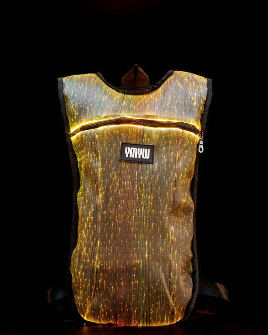 Fiber optic light up hydration backpack glowing in golden light with YMYW logo visible on a dark background