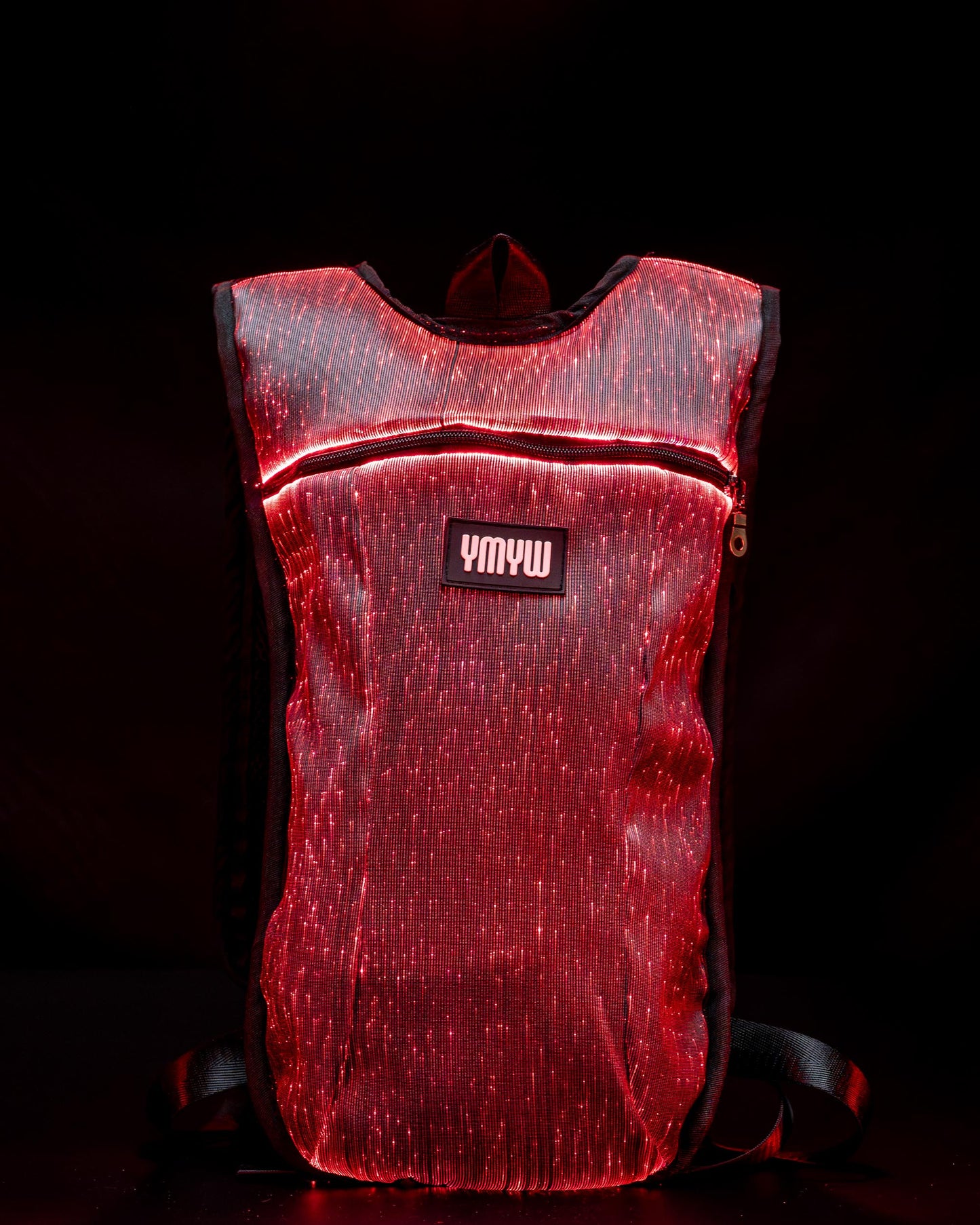 Fiber optic light up hydration backpack glowing in red light with YMYW logo visible on a dark background