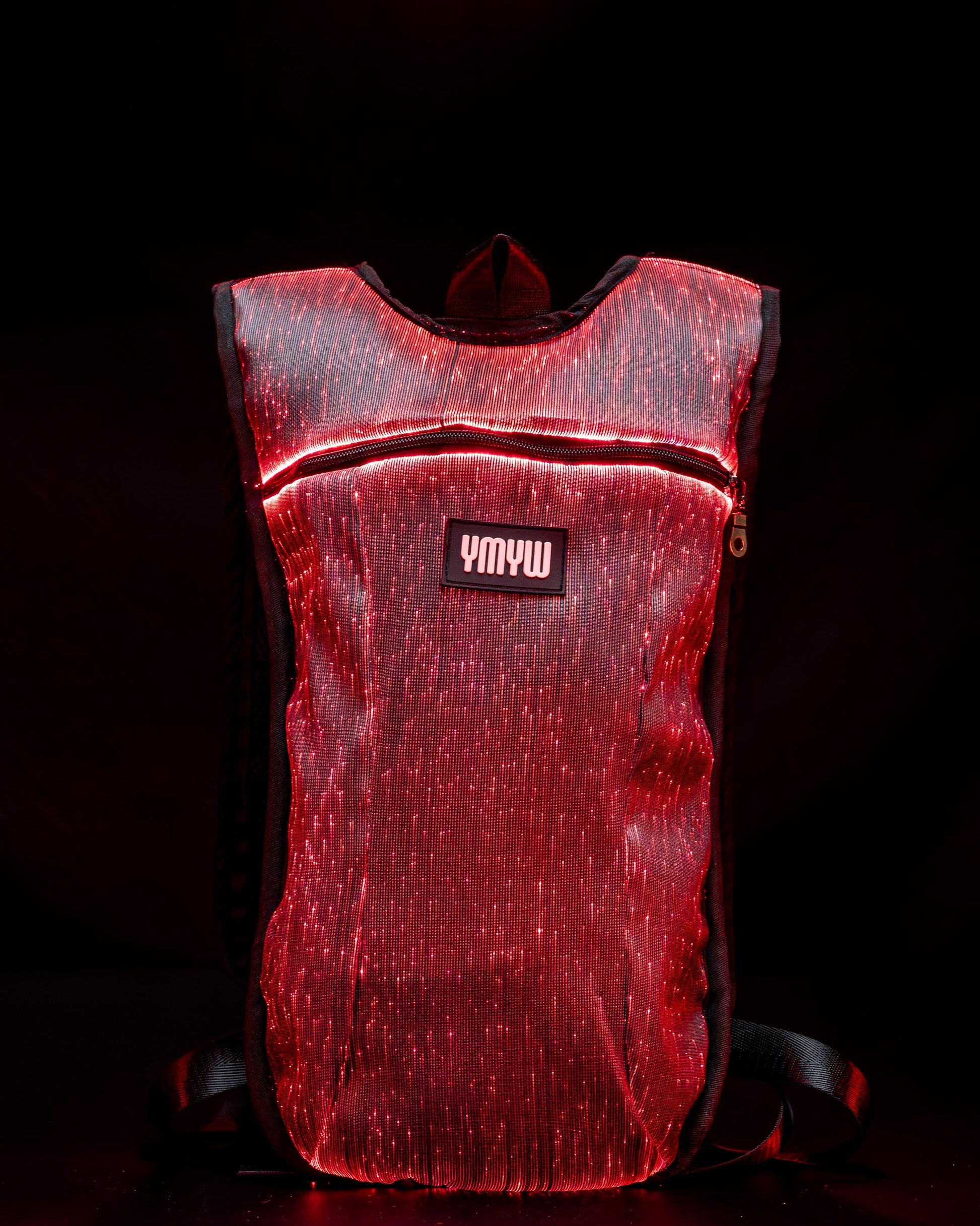 Fiber optic light up hydration backpack glowing in red light with YMYW logo visible on a dark background