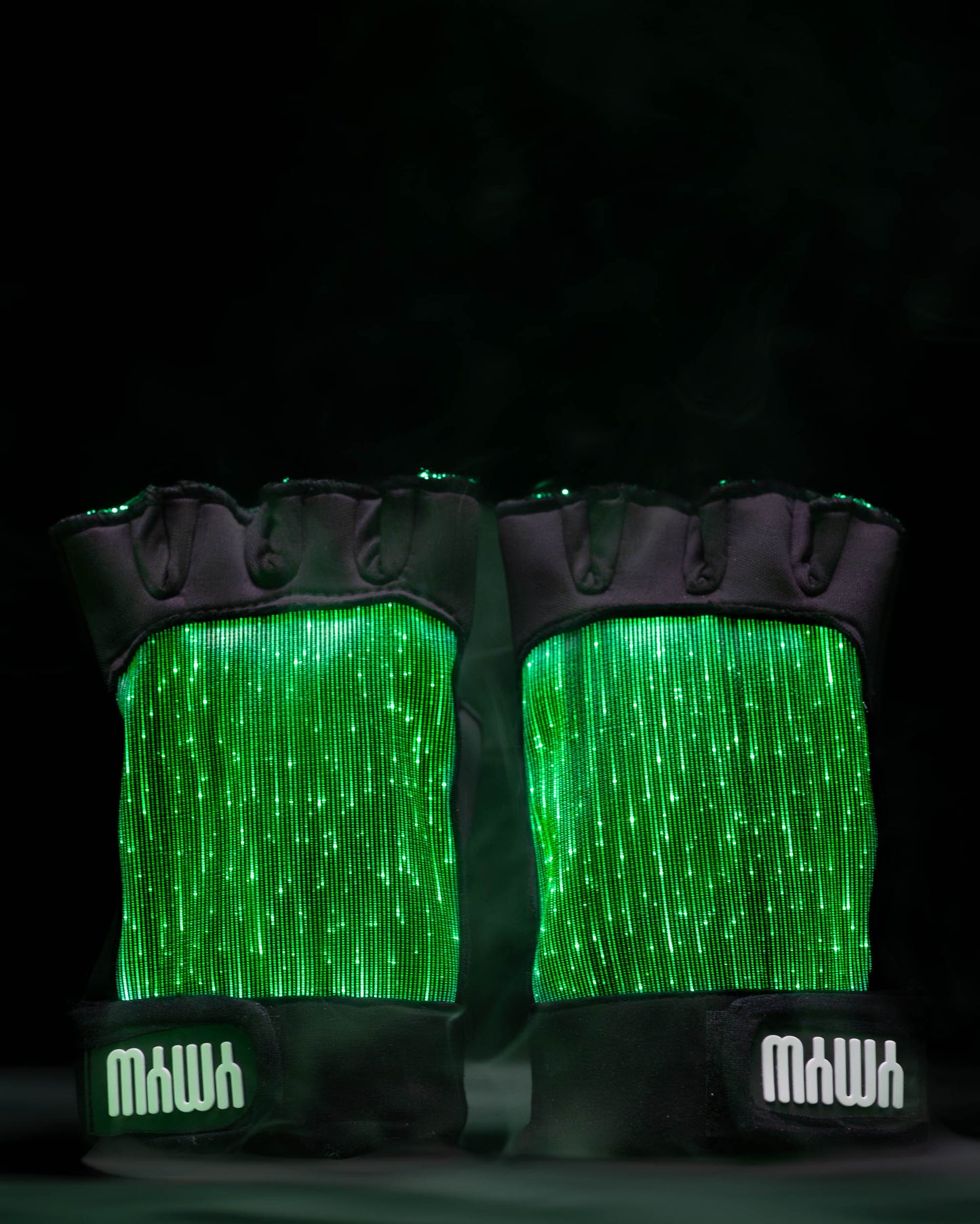 Pair of black fiber optic light up gloves illuminated in green light against a dark background