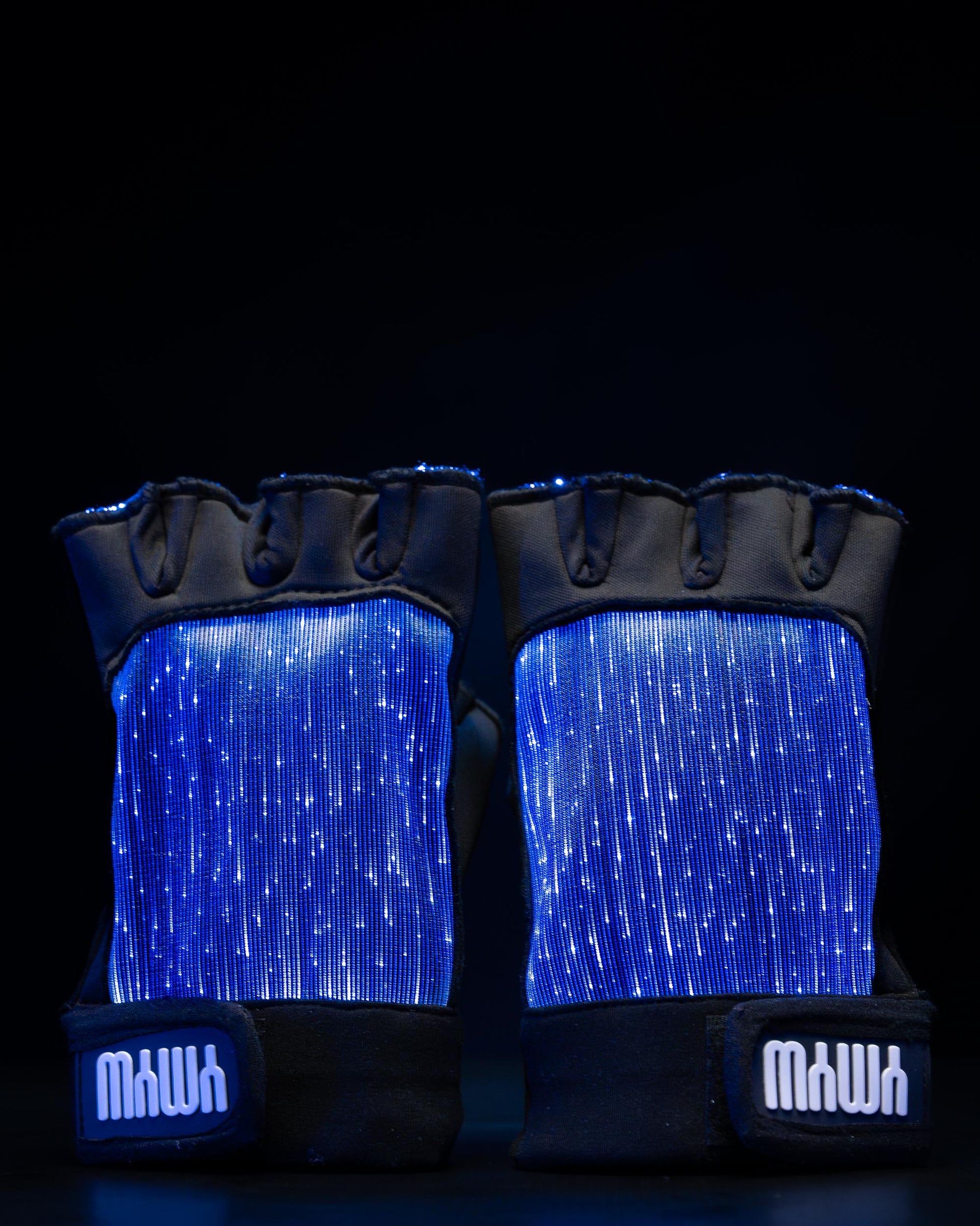 Pair of black fiber optic light up gloves illuminated in blue light against a dark background