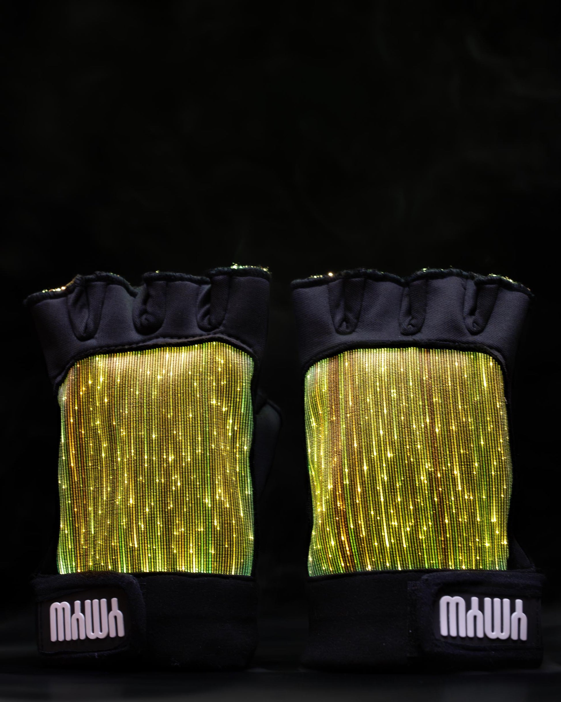 Pair of black fiber optic light up gloves illuminated in gold light against a dark background
