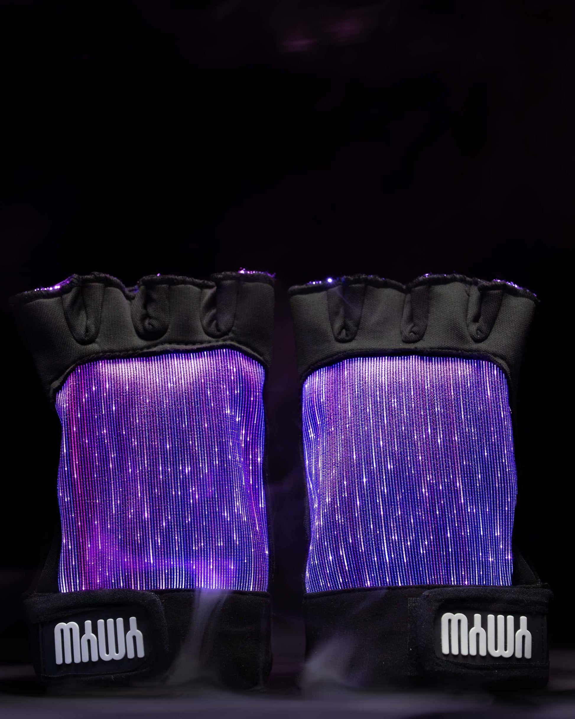Pair of black fiber optic light up gloves illuminated in purple light against a dark background