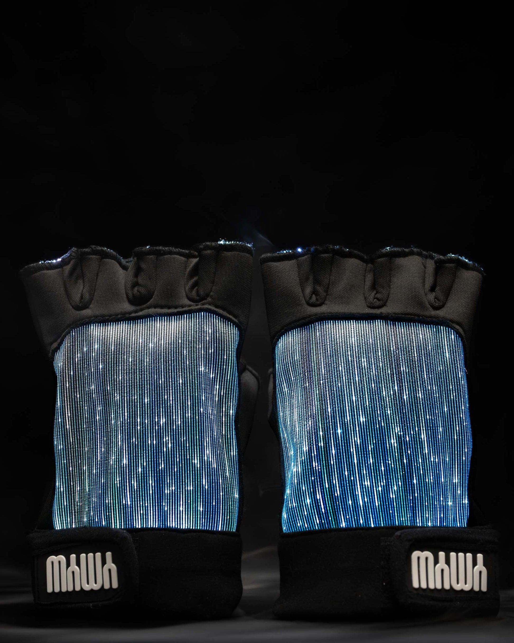 Pair of black fiber optic light up gloves illuminated in light blue against a dark background