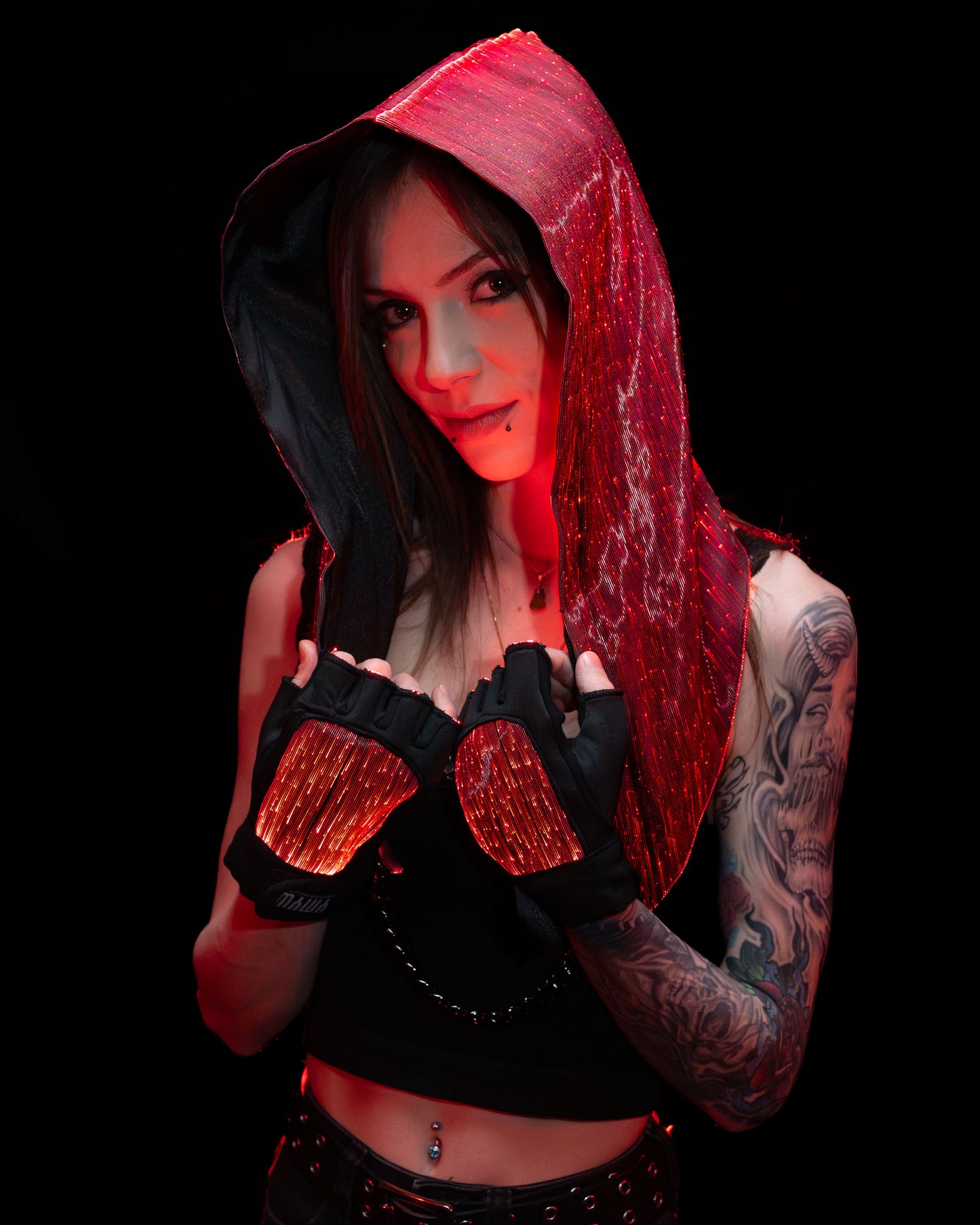 Woman wearing a fiber optic light-up hood and gloves illuminated in red light against a dark background