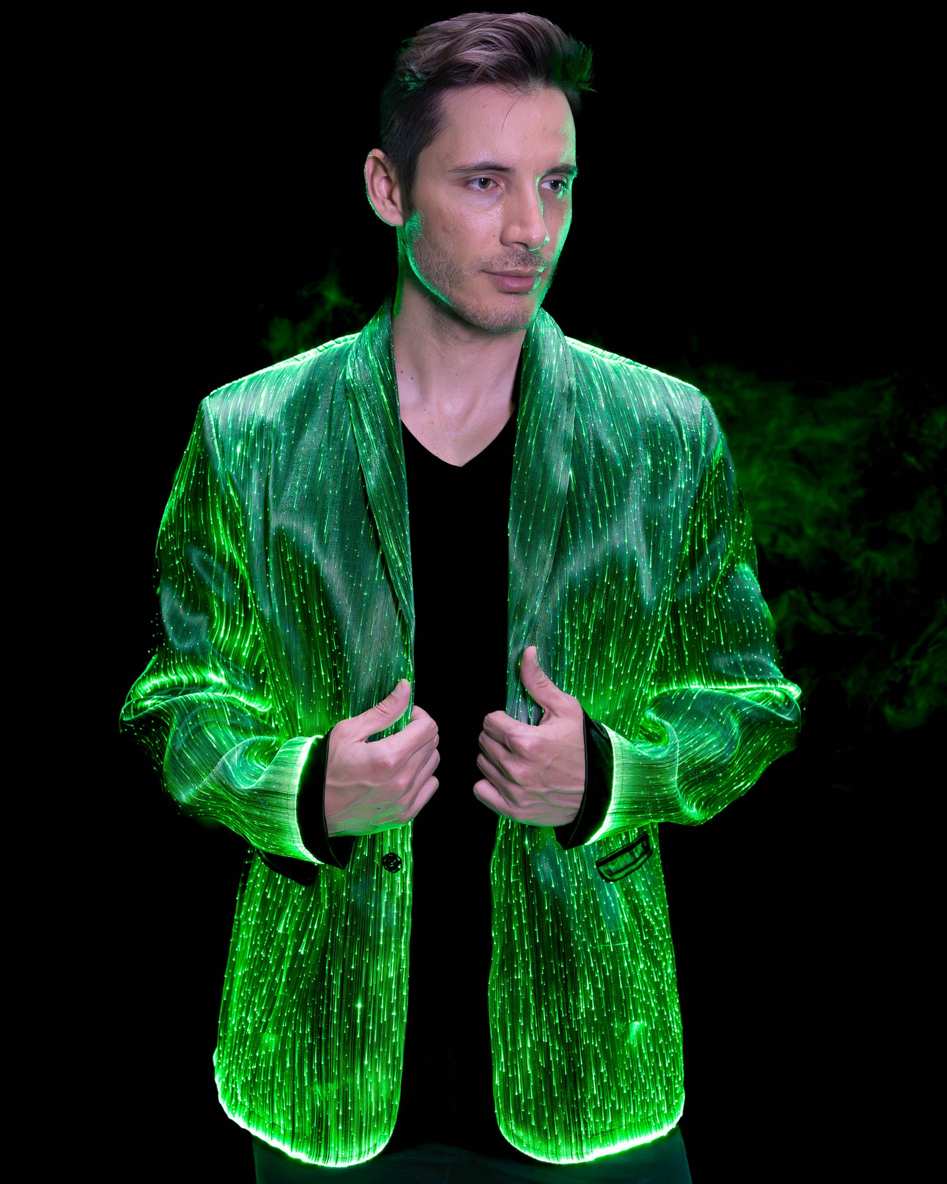 Man wearing a fiber optic light-up suit jacket illuminated in green light against a dark background