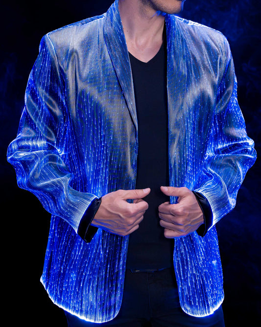 Man wearing a fiber optic light-up suit jacket illuminated in blue light against a dark background