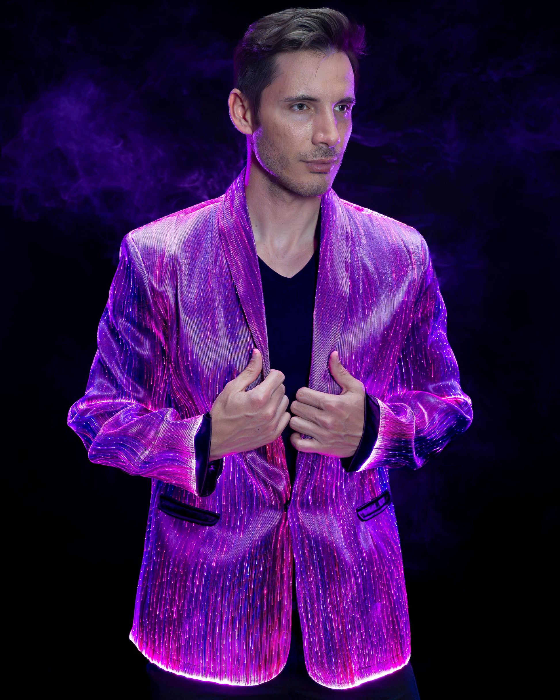 Man wearing a fiber optic light-up suit jacket illuminated in purple light against a dark background