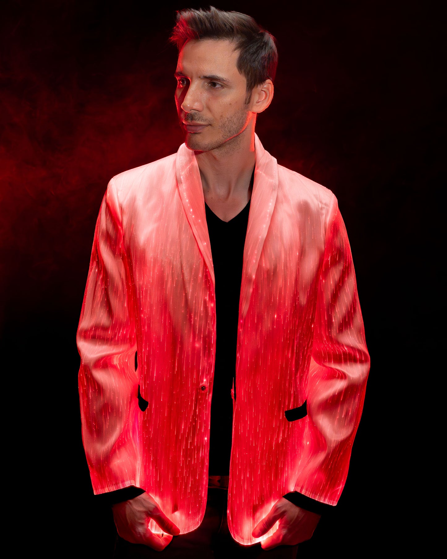 Man wearing a white fiber optic light up suit jacket glowing in red light against a dark background