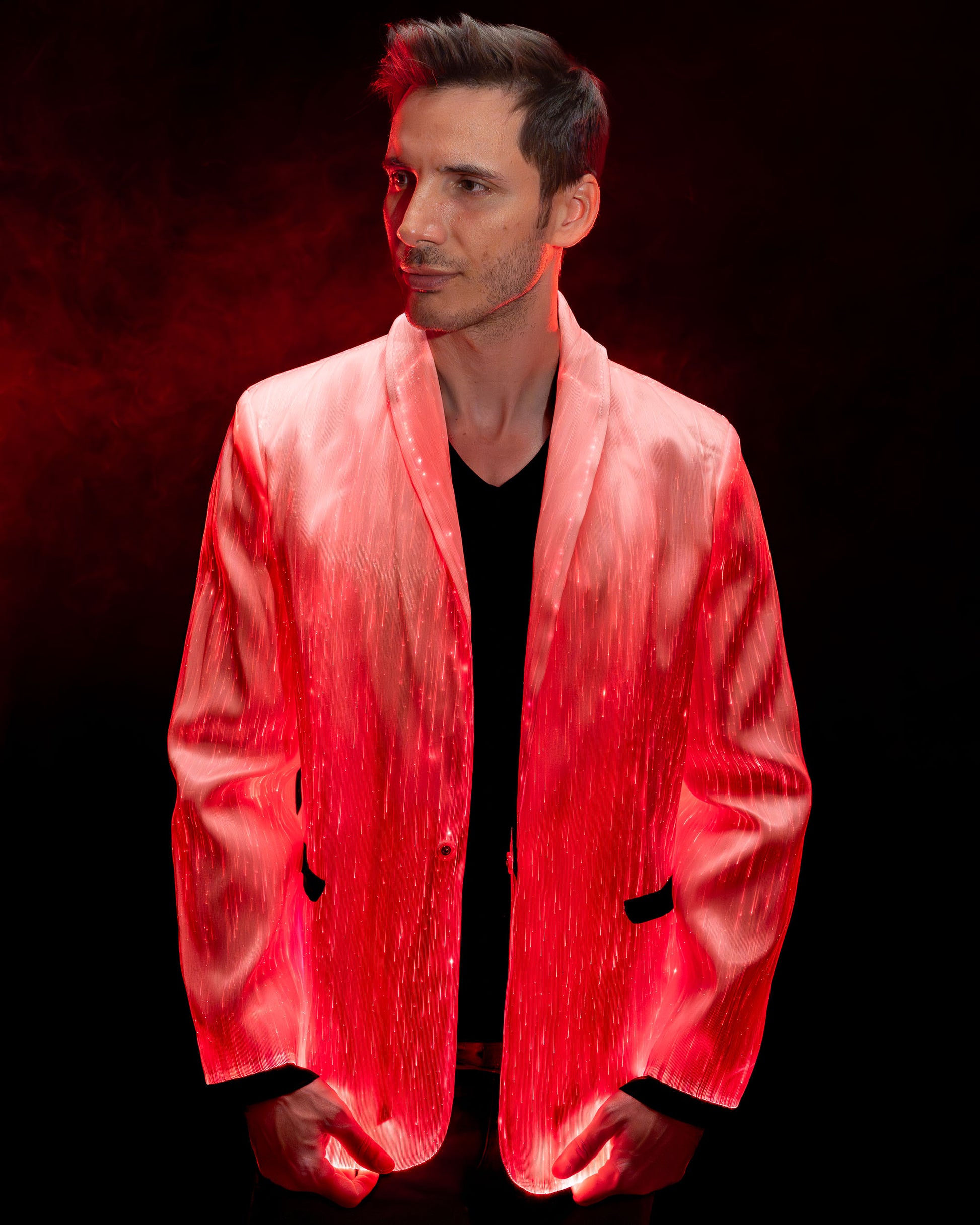 Man wearing a white fiber optic light up suit jacket glowing in red light against a dark background