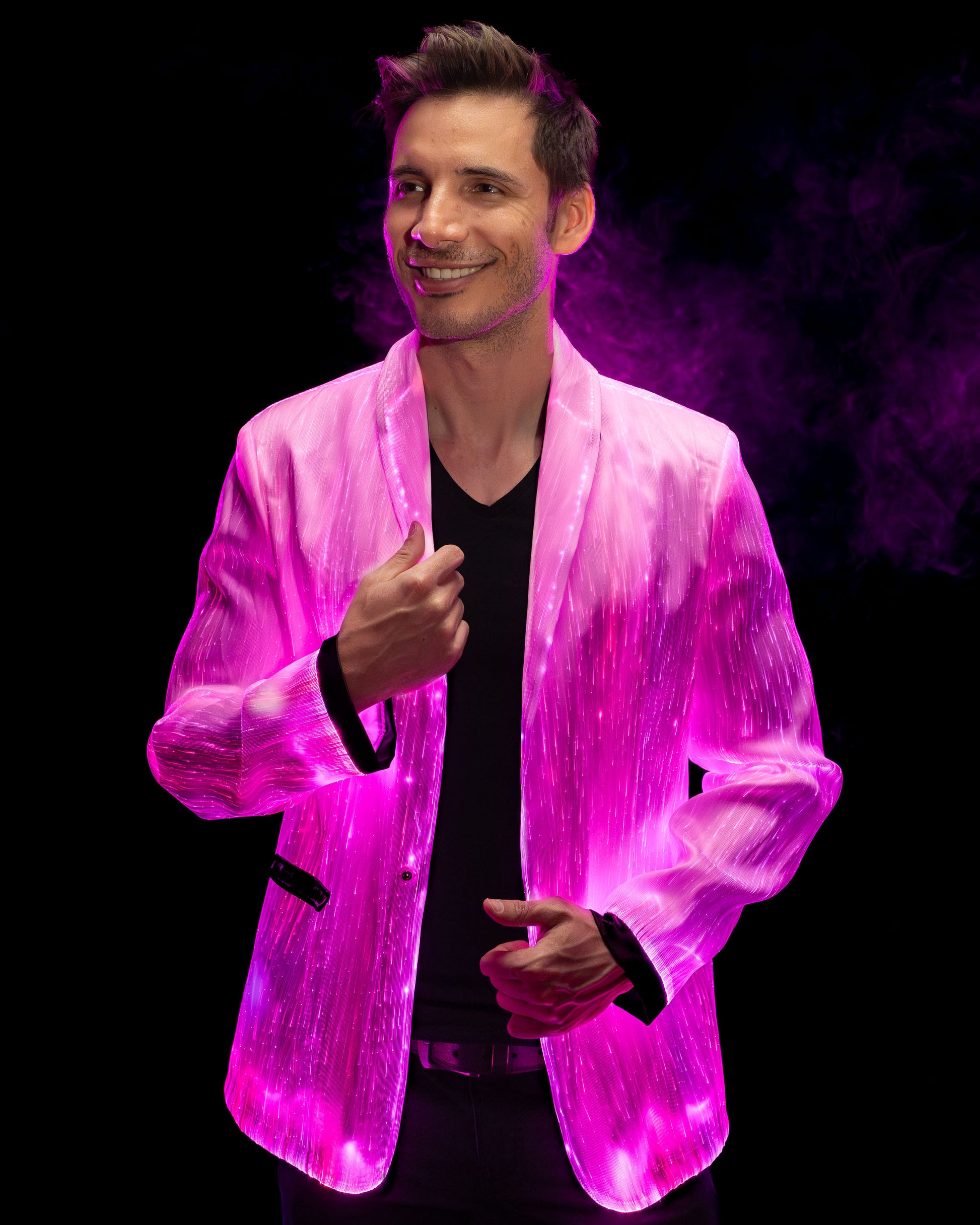 Man wearing a white fiber optic light up suit jacket glowing in pink light against a dark background