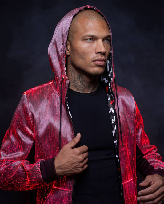 Man wearing a glowing red fiber-optic hoodie with the hood up, standing against a dark smoke-filled background