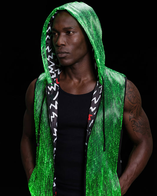 Man wearing a glowing green sleeveless fiber-optic hoodie, standing against a black background with the hood up