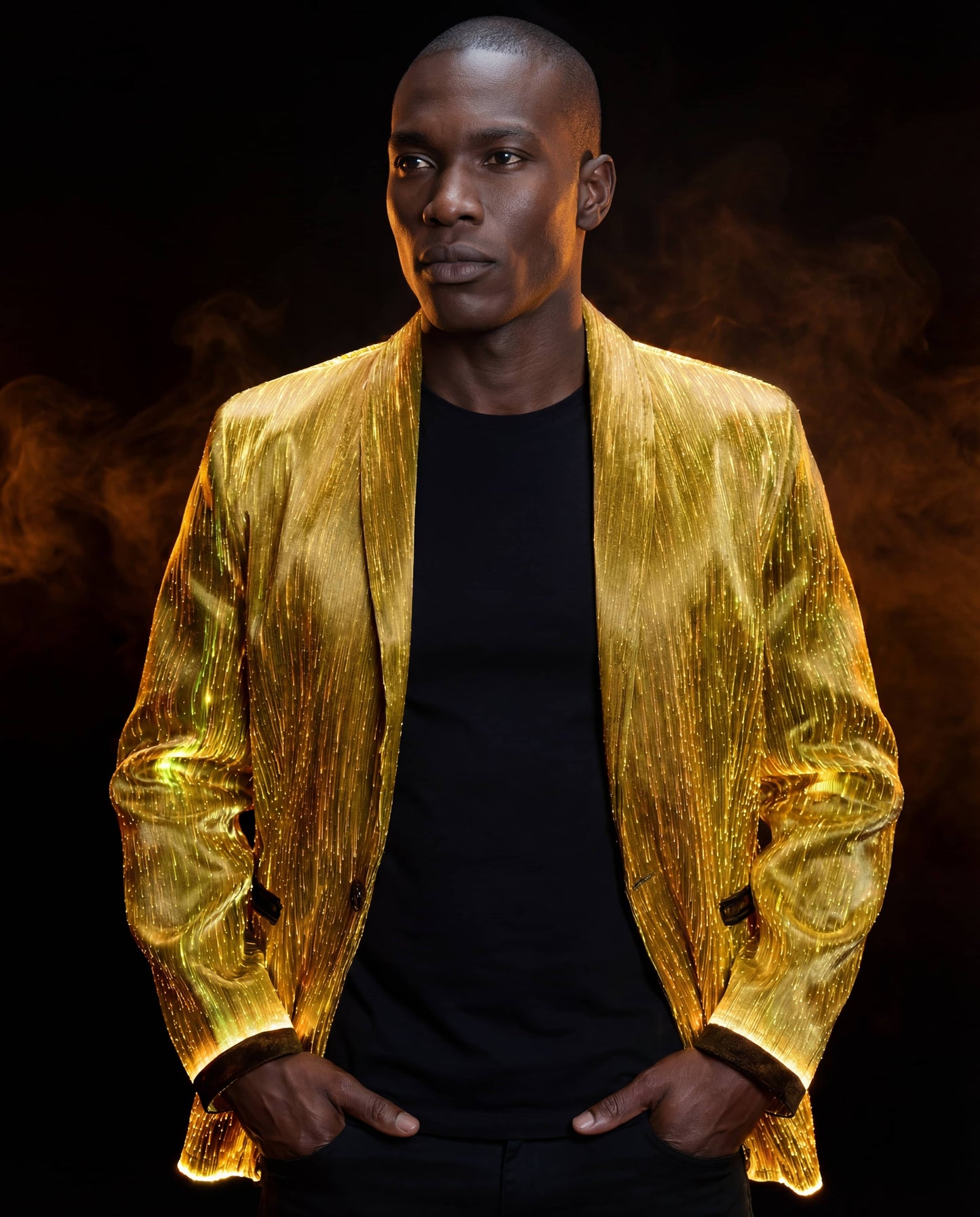 Man wearing a glowing gold fiber-optic suit jacket, standing against a dark background with warm orange smoke behind him