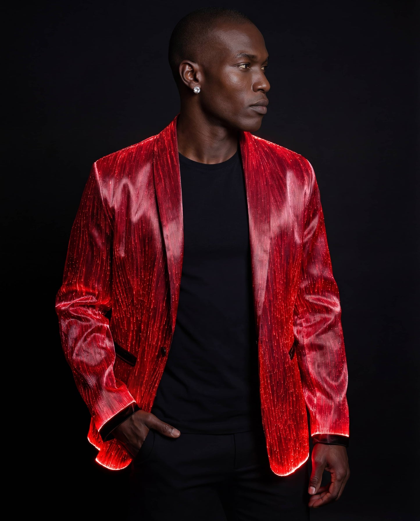 Man wearing a glowing red fiber-optic suit jacket, standing against a black background with subtle red light reflecting across the fabric