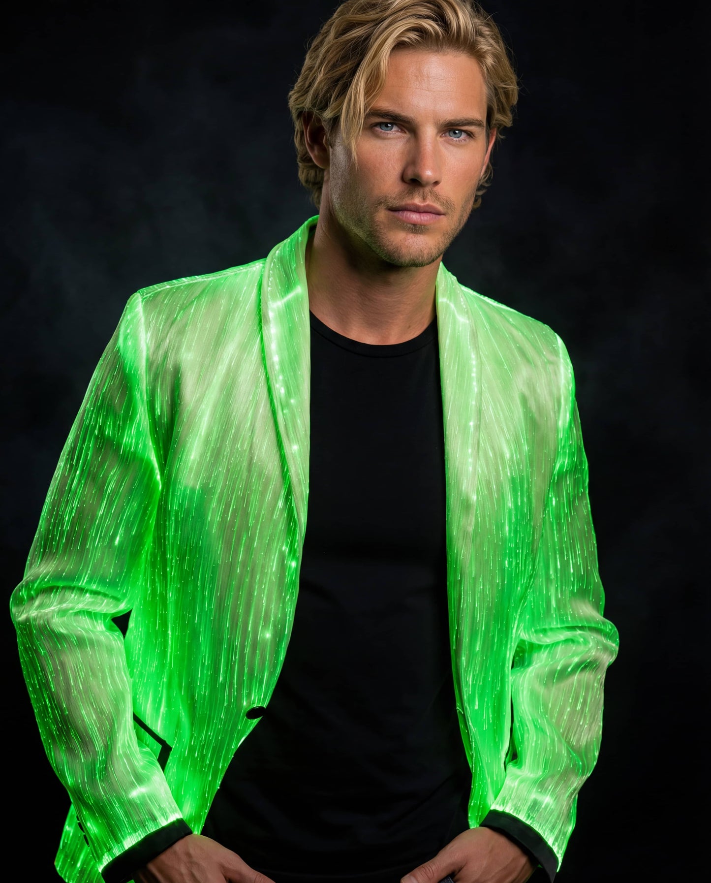 Man wearing a glowing green fiber-optic suit jacket, standing against a dark smoky background with his hands in his pockets