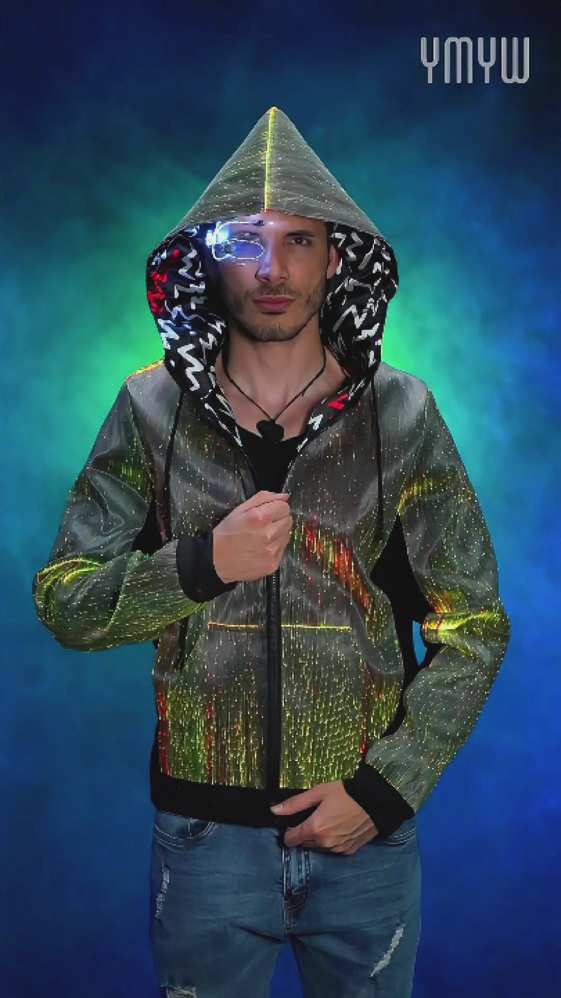 Man wearing a fiber optic LED hoodie with the hood up, rotating slowly on a platform as the jacket glows in shifting colors against a colorful, smoky background
