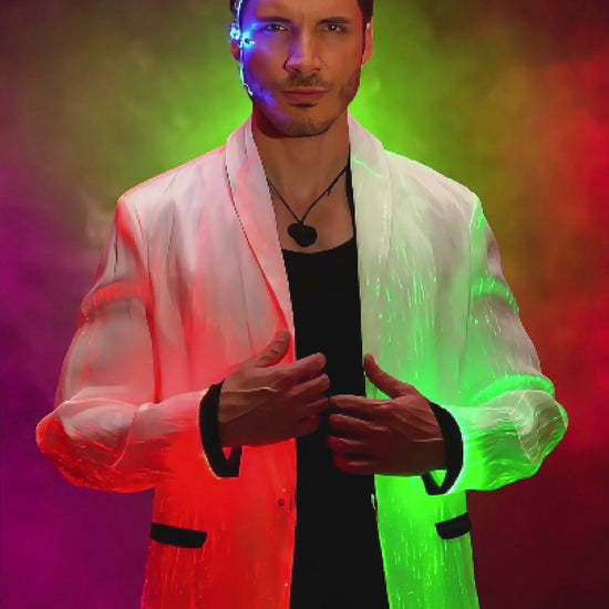Man wearing a black fiber optic LED suit jacket illuminated in shifting colors, standing against a smoky gradient background. The jacket glows through embedded optic fibers with changing blue, pink, and purple light