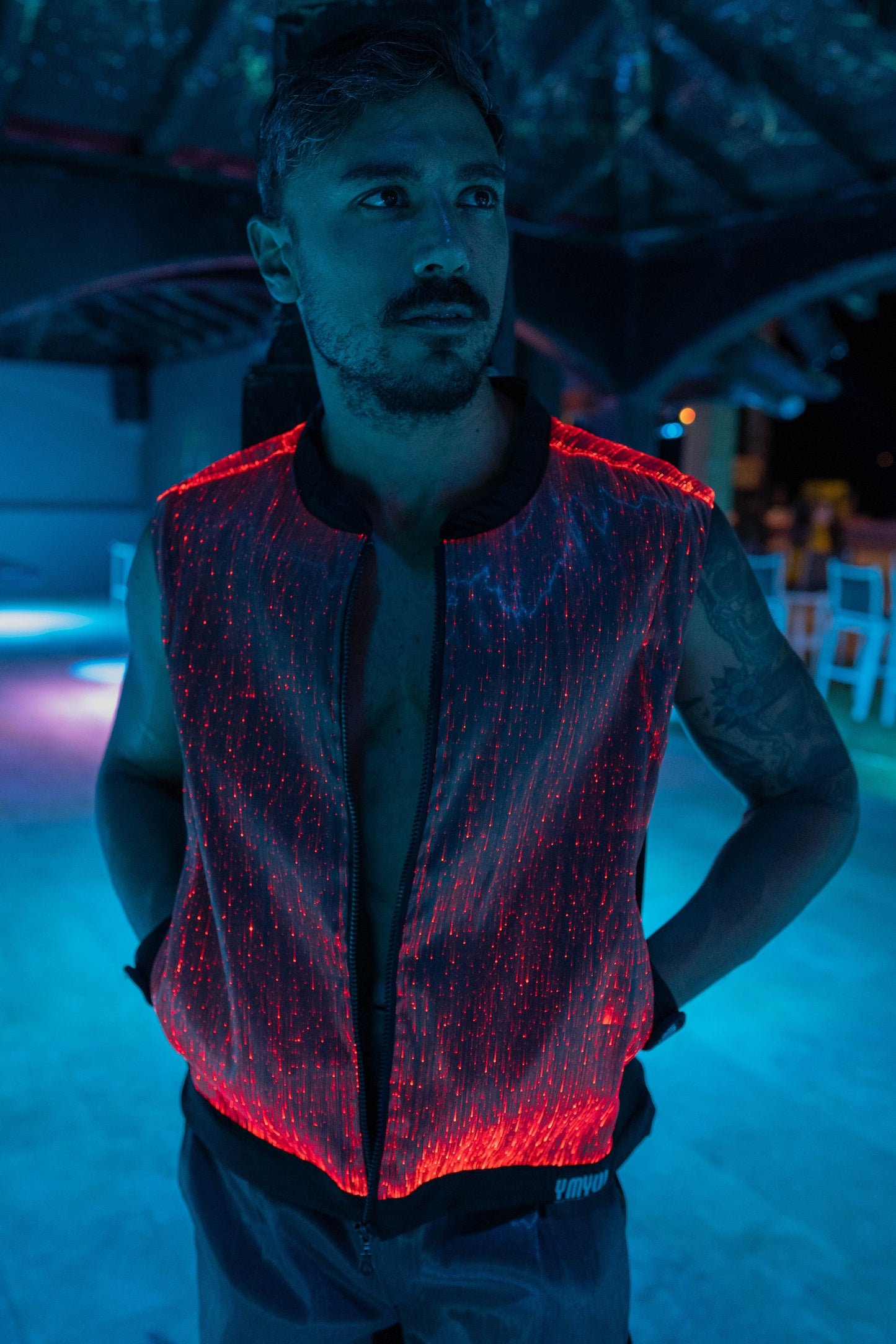 Man wearing a black fiber optic light up vest illuminated in red light against a dark background